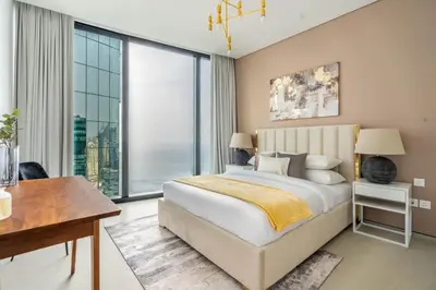 a bedroom with a bed and a desk and a large window at GuestReady - Above the clouds in Dubai Marina in Dubai