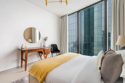 a bedroom with a bed and a desk and a large window at GuestReady - Above the clouds in Dubai Marina in Dubai