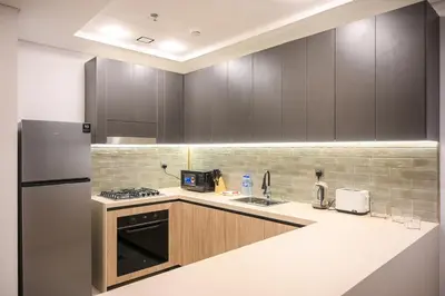 a kitchen with wooden cabinets and a refrigerator at Luxurious New 1BR Apt Prime Jumeirah Garden City in Dubai