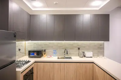 a kitchen with wooden cabinets and a sink at Luxurious New 1BR Apt Prime Jumeirah Garden City in Dubai