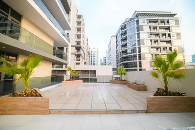 a courtyard in a building with palm trees and buildings at Luxurious New 1BR Apt Prime Jumeirah Garden City in Dubai