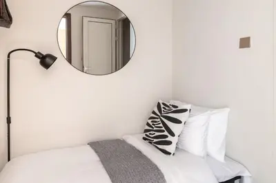 a mirror on a wall above a bed with a pillow at Frank Porter - Eleganz by Danube in Dubai