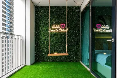 a room with a green wall with a sign on it at Amazing Patio Experience - Best Burj Khalifa View in Dubai
