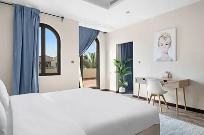 a white bedroom with a bed and a desk at Beachfront Dubai Villa for 10 Guests with Full Kitchen & View in Dubai