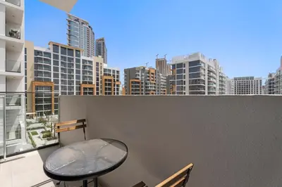 a table and stool on a balcony with a city skyline at StoneTree - Azizi Riviera 36 Studio - Brand new in Dubai