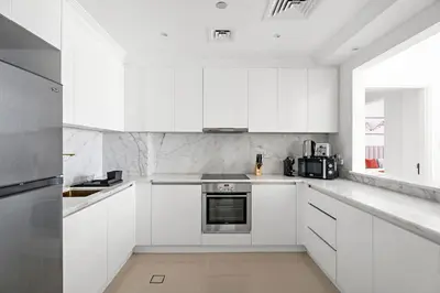 a white kitchen with white cabinets and a window at Stonetree - Golden Mile 4 - Beach Access in Dubai