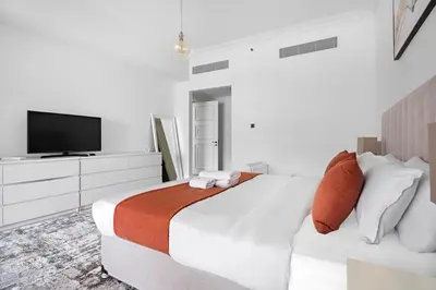 a white bedroom with a large bed and a flat screen tv at Stonetree - Golden Mile 4 - Beach Access in Dubai