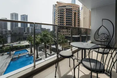 a balcony with a table and chairs and a pool at izzzi - One Bedroom Apartment, Sparkle Tower in Dubai