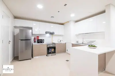 a kitchen with white cabinets and a stainless steel refrigerator at Al Andalus D I Jumeirah Golf Estates in Dubai