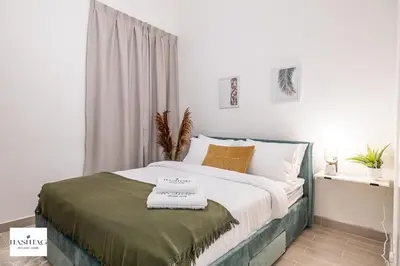 a white bedroom with a bed with a green blanket at Al Andalus D I Jumeirah Golf Estates in Dubai