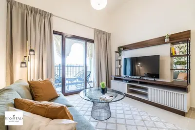 a living room with a couch and a tv at Al Andalus D I Jumeirah Golf Estates in Dubai