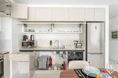 a kitchen with white cabinets and a table at Silkhaus Chic 1BDR in Exclusive Neighbourhood in Dubai