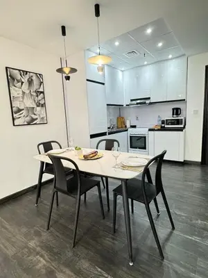 a dining room table with chairs and a kitchen at Stay in brand new Luxury Sport City apartment 15 in Dubai