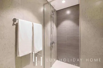 a bathroom with a shower with white towels at LUX The Dubai Hills Executive Suite in Dubai