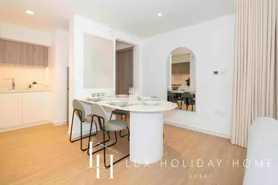 a kitchen and dining room with a white table and chairs at LUX The Dubai Hills Executive Suite in Dubai