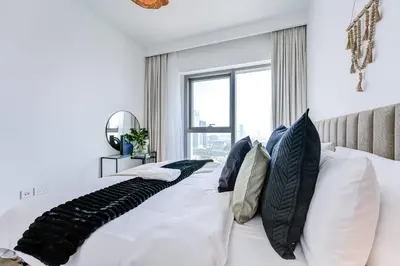 a bedroom with a white bed with pillows and a window at Silkhaus High Floor 1 BDR In The Heart of Downtown in Dubai