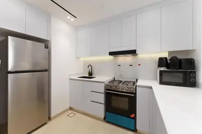 a white kitchen with a stove and a microwave at Experience Serenity at Binghatti Crest in JVC in Dubai