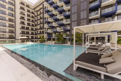 a large swimming pool with lounge chairs in front of a building at Experience Serenity at Binghatti Crest in JVC in Dubai