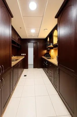 a large kitchen with wooden cabinets and white tile floors at The residences 1 - Luxury 1BR apt in Downtown Dubai - 2 mins walk to Burj Khalifa & Dubai Mall in Dubai