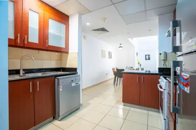 a kitchen with wooden cabinets and a stainless steel dishwasher at RH- Walk to JBR beach & Tram, Comfortable 02BR in Dubai