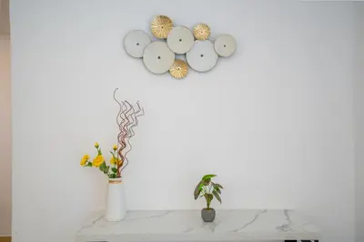a white wall with a clock and a vase with a plant at RH- Walk to JBR beach & Tram, Comfortable 02BR in Dubai