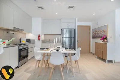 a kitchen with a white table and white chairs at Vogue Creek Harbour Breeze Creek Beach Waterfront Living Close to Downtown, Burj Khalifa and Dubai Mall, Two Bedroom apartment With Balcony and Private Manmade Beach, Access to all Amenities in Dubai