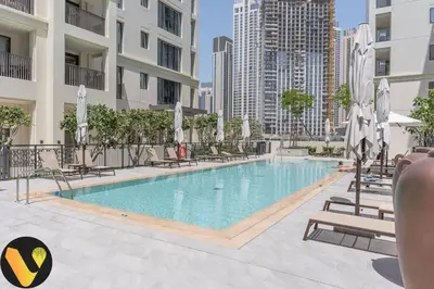a pool with chairs and umbrellas in a building at Vogue Creek Harbour Breeze Creek Beach Waterfront Living Close to Downtown, Burj Khalifa and Dubai Mall, Two Bedroom apartment With Balcony and Private Manmade Beach, Access to all Amenities in Dubai