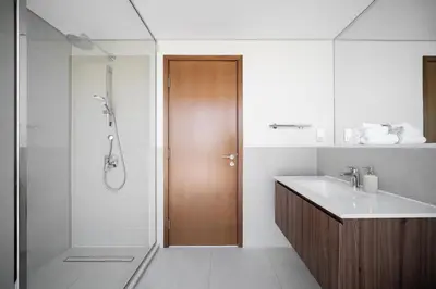 a bathroom with a shower and a wooden door at Vida Voyage - Vida Residences - Creek Harbour in Dubai