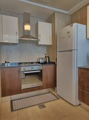 a kitchen with a white refrigerator and a stove at 1 Bed room - Azizi Daisy - Furjan in Dubai