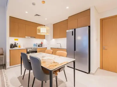 a kitchen with a table and a stainless steel refrigerator at Ravishing Retreat 2BR Creek Beach Luxury Abode in Dubai