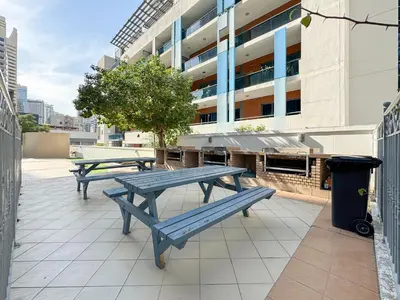 two picnic tables on a patio in front of a building at Trophy - Magical Marina 1BDR connected to Metro Station in Dubai