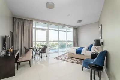 a bedroom with a bed and a table and chairs at Nasma Luxury Stays - Charming Studio at DAMAC Hills Artesia Tower C in Dubai