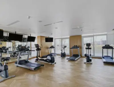 a gym with several treadmills and elliptical machines at Nasma Luxury Stays - Charming Studio at DAMAC Hills Artesia Tower C in Dubai