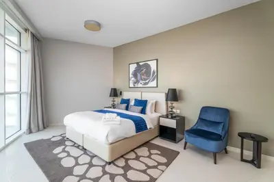 a bedroom with a bed and a blue chair at Nasma Luxury Stays - Charming Studio at DAMAC Hills Artesia Tower C in Dubai
