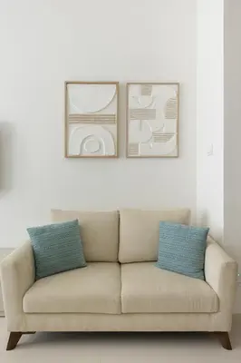 a couch in a living room with two pictures on the wall at Chic Palm Studio with Infinity Pool in Dubai