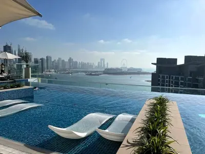 a swimming pool with chairs on the roof of a building at Chic Palm Studio with Infinity Pool in Dubai