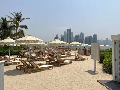 a bunch of chairs and umbrellas on a beach at Chic Palm Studio with Infinity Pool in Dubai