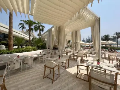 a restaurant with white tables and white chairs at Chic Palm Studio with Infinity Pool in Dubai