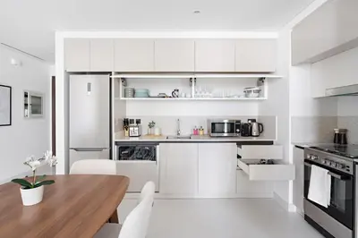 a kitchen with white cabinets and a wooden table at Silkhaus Sea & Palm View 1BDR in Marina Vista in Dubai