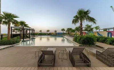 a large swimming pool with chairs and palm trees at Aykon Luxury Sky Collection Suites with Balcony & Sea View by HSHOME in Dubai