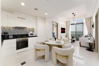 a white kitchen and living room with a table and chairs at Aykon Luxury Sky Collection Suites with Balcony & Sea View by HSHOME in Dubai