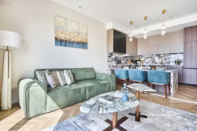 a living room with a green couch and a kitchen at Frank Porter - Emaar Residences Dubai Marina in Dubai
