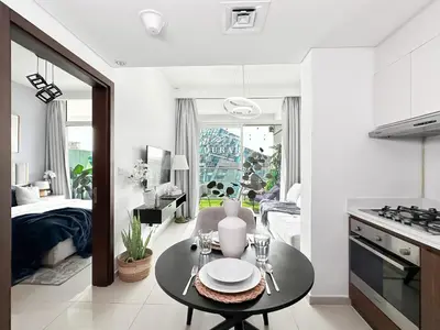 a living room with a table and a kitchen at Trophy - Springs Suite with Cozy Balcony Garden in Dubai