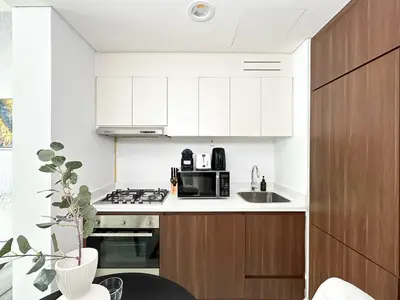 a kitchen with white cabinets and a sink at Trophy - Springs Suite with Cozy Balcony Garden in Dubai