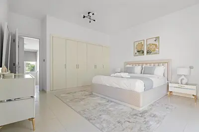 a white bedroom with a large bed and a dresser at Whole 3 BR with Maids Room House - The Springs - Privat Garden in Dubai