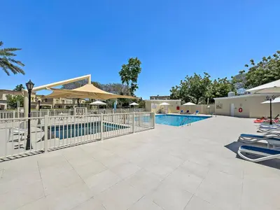 a swimming pool with lounge chairs and umbrellas at Whole 3 BR with Maids Room House - The Springs - Privat Garden in Dubai