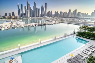 a large swimming pool with a city skyline in the background at Marina Vista 1BR Sea View Luxury Escape in Dubai