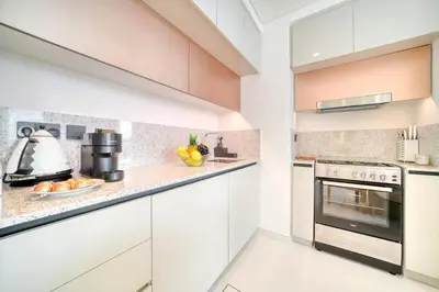 a kitchen with white cabinets and a stove at Marina Vista 1BR Sea View Luxury Escape in Dubai