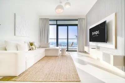 a white living room with a white couch and a tv at Marina Vista 1BR Sea View Luxury Escape in Dubai
