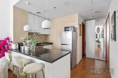 a kitchen with a counter and chairs and a refrigerator at WelHome - Relaxing and Fancy Studio Apt with City View in Dubai